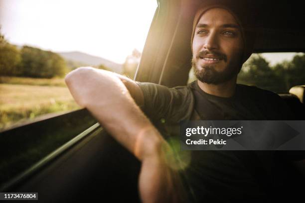 hipster man enjoying the ride on the back seat in car - car passenger stock pictures, royalty-free photos & images