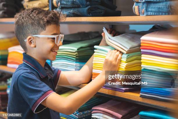 jongen kiezen van een shirt in de kledingwinkel - boy clothes stockfoto's en -beelden