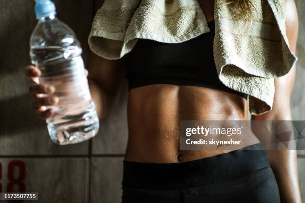 unrecognizable athletic woman with abdominal muscles on water break in dressing room. - woman backstage stock pictures, royalty-free photos & images