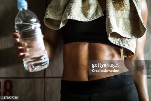 unrecognizable athletic woman with abdominal muscles on water break in dressing room. - abs fotos imagens e fotografias de stock