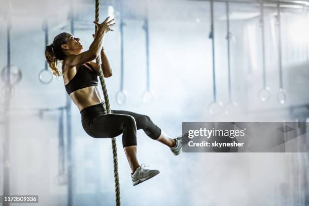muscolosa donna atletica costruire salendo la corda in una palestra. - cross training foto e immagini stock