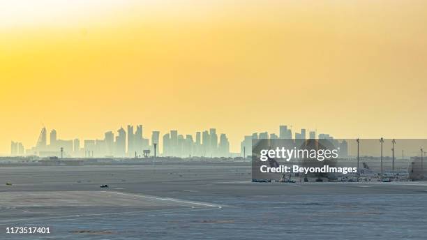 panoramic view of doha city silhouette from airport terminal - doha sunset stock pictures, royalty-free photos & images