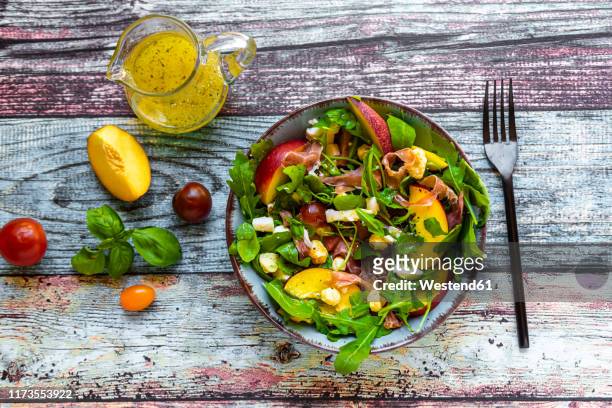 directly above view of fresh salad bowl with fork and pitcher on table - nectarine stock-fotos und bilder