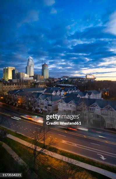 vehicles on street by buildings in charlotte against cloudy sky during sunset - charlotte north carolina neighborhood stock pictures, royalty-free photos & images