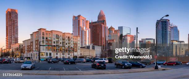 panoramic view of cars in parking lot by buildings against clear sky during sunset - charlotte north carolina stock pictures, royalty-free photos & images