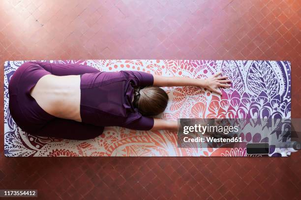 young brunette woman practising yoga in student dorm, child position from above - brunette woman bedroom stock-fotos und bilder