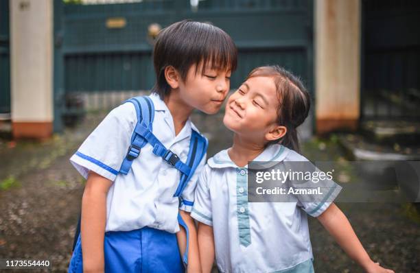 young chinese girl smiling and enduring brotherly affection - boy girl kissing stock pictures, royalty-free photos & images