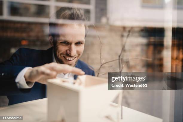 smiling businessman with architectural model - person in suit construction stock-fotos und bilder