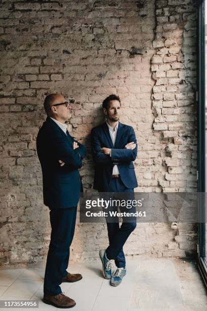 senior and mid-adult businessman standing at brick wall - successor 個照片及圖片檔