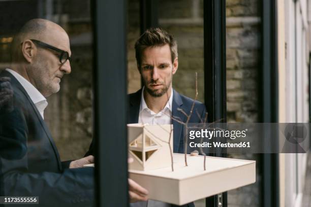 senior and mid-adult businessman with architectural model - architekturmodell stock-fotos und bilder