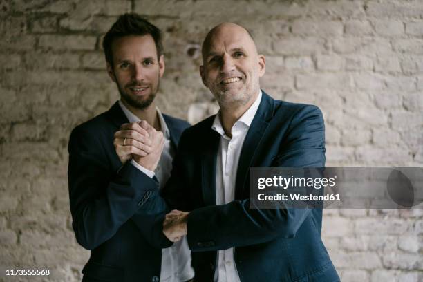 portrait of confident mid-adult and senior businessman shaking hands - father son business europe stock pictures, royalty-free photos & images