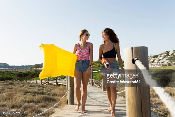 young women with yellow airbed and sunshade walking to the beach - ironia imagens e fotografias de stock