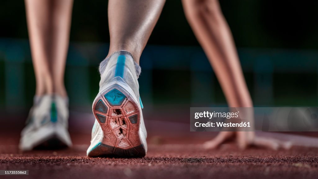 Legs of female athlete running on tartan track
