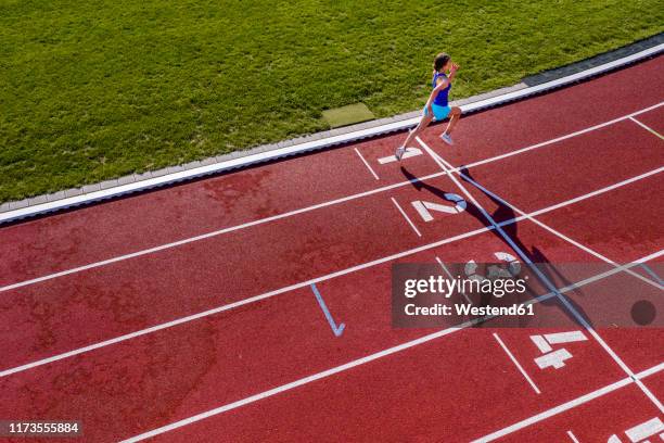 aerial view of a running young female athlete on a tartan track crossing finishing line - finishing line stock pictures, royalty-free photos & images