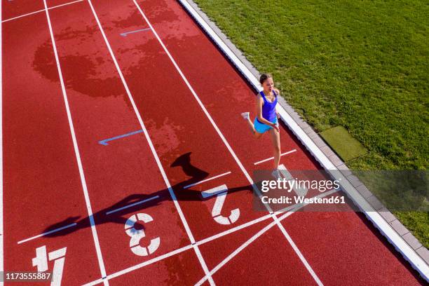 aerial view of a running young female athlete on a tartan track crossing finishing line - crossing the finishing line stock pictures, royalty-free photos & images