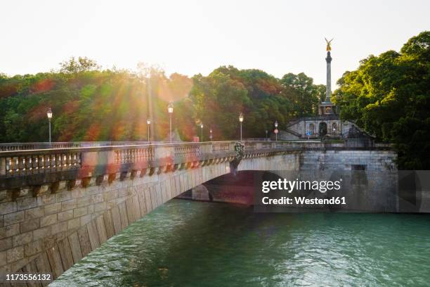 germany, upper bavaria, munich, luitpoldbrucke crossing isar river with angel of peace in background - río isar fotografías e imágenes de stock