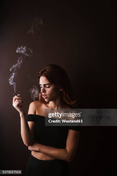 young woman smoking marihuana at home - human joint stock-fotos und bilder