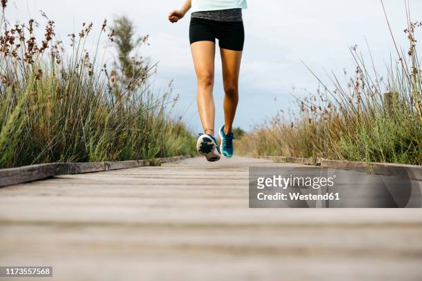 female jogger running on wooden walkway - running shoes sky stock pictures, royalty-free photos & images