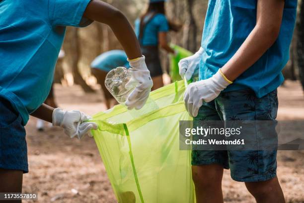 close-up of volunteering children collecting garbage in a park - giving tuesday stock pictures, royalty-free photos & images