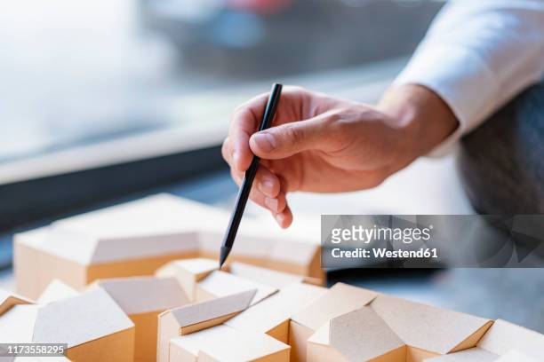 close-up of man with pencil pointing at architectural model in office - architekturmodell stock-fotos und bilder