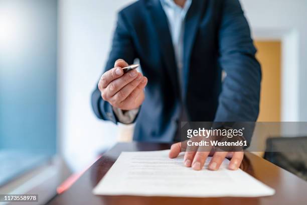 close-up of businessman in office presenting ballpen and contract - human body part stock pictures, royalty-free photos & images