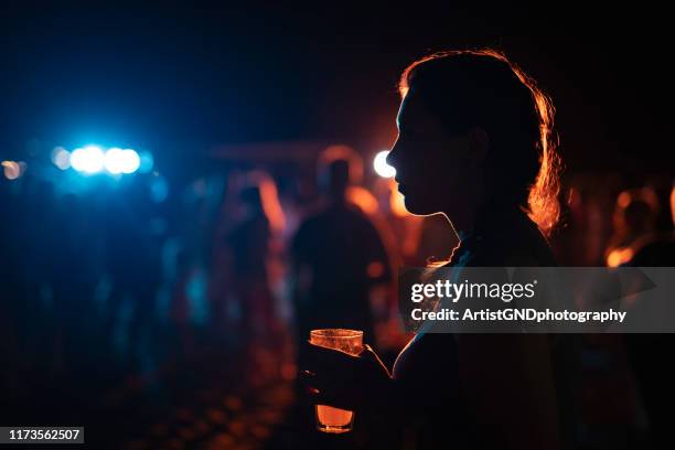 donna solitaria che beve alla festa all'aperto. - locale notturno foto e immagini stock