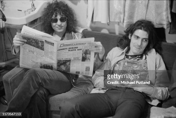 Singer Marc Bolan , on left, and percussionist Mickey Finn of English glam rock group T Rex, together on a sofa reading a copy of the local Cardiff...