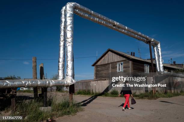 Woman walks under a pipe built above ground due to the permafrost that the city is built upon in Yakutsk, Russia on July 2, 2019. Yakutsk is...