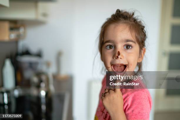 girl eating chocolate with her finger - cooking mess imagens e fotografias de stock