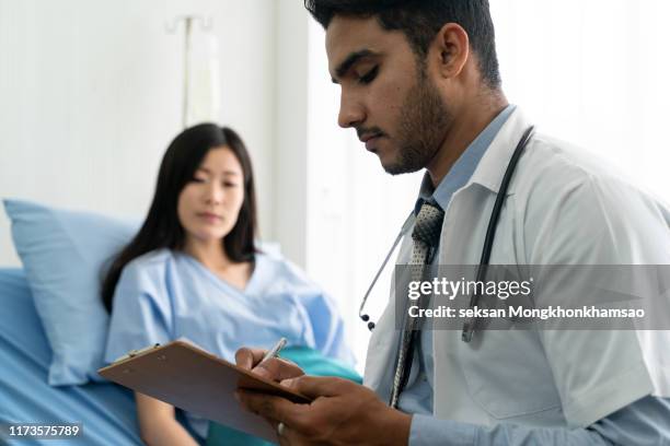 doctor woman sitting with male patient at the desk - doctor general practitioner stock pictures, royalty-free photos & images