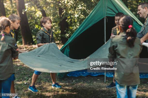 group of scouts building a tent - girl guide association stock pictures, royalty-free photos & images