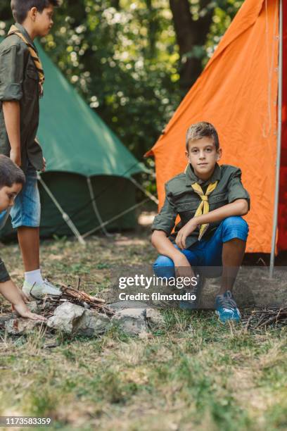 group of scouts roast marshmallow candies on campfire in forest - boy scout stock pictures, royalty-free photos & images