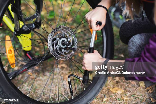 vrouw repareren fiets in de natuur. - pomp stockfoto's en -beelden