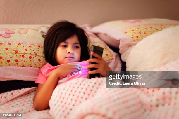 Child Looking at Phone in Her Bed