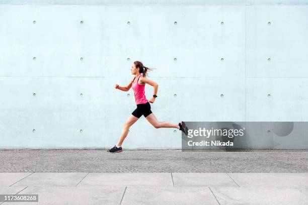 giovane donna sportiva che corre davanti al muro di cemento - rosa germanica foto e immagini stock