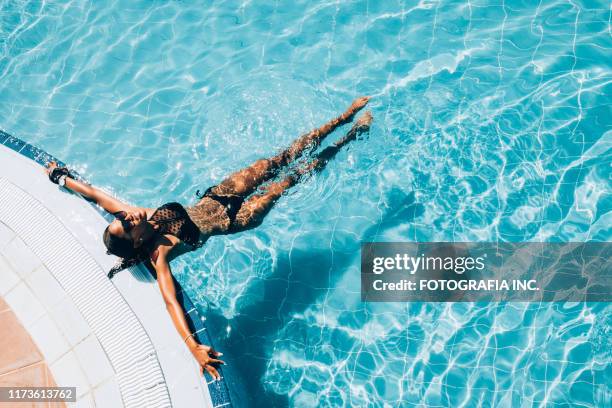 jeune femme noire à la piscine de ressource - piscine de complexe balnéaire photos et images de collection