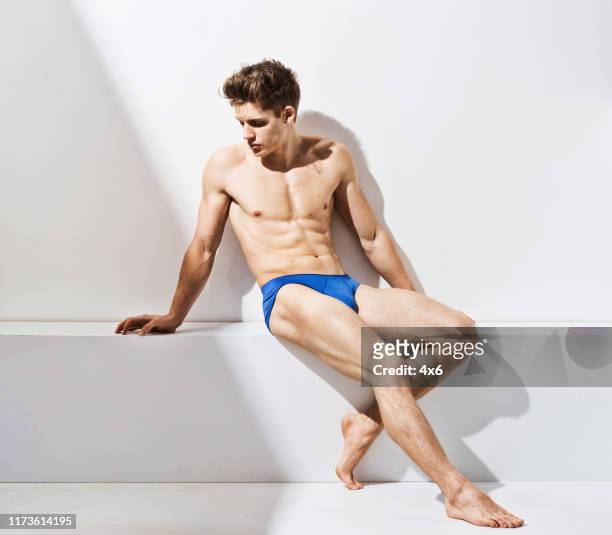 full length / one man only of 20-29 years old adult handsome people caucasian male / young men sitting / resting in front of white background wearing underwear / men's underpants / semi-dress with shadow - men underware model stock pictures, royalty-free photos & images