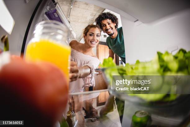若い女性と男が冷蔵庫のドアを開ける - open fridge ストックフォトと画像