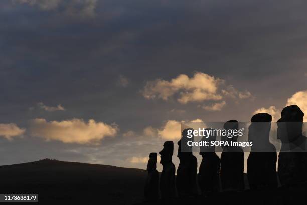 Silhouette of Moais at ceremonial platform Ahu Tongariki seen during dawn at Rapa Nui National Park. Moais are monolithic human figures which...