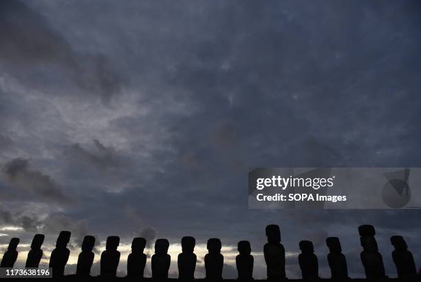 Silhouette of Moais at ceremonial platform Ahu Tongariki seen during dawn at Rapa Nui National Park. Moais are monolithic human figures which...
