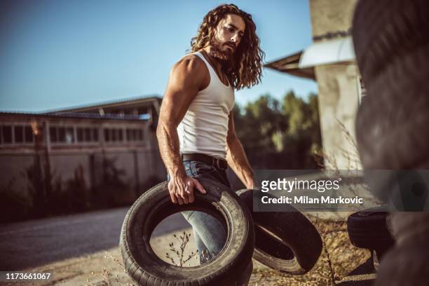 pneus do automóvel do armazém - handsome muscle men - fotografias e filmes do acervo