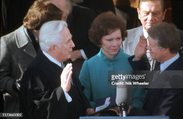 President Jimmy Carter with wife Rosalyn Carter, takes the oath of office from Chief Justice of the Supreme Court Warren Burger on stage in front of...