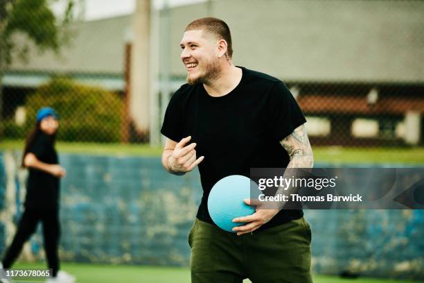 laughing man playing dodgeball with friends - dodgeball stock pictures, royalty-free photos & images