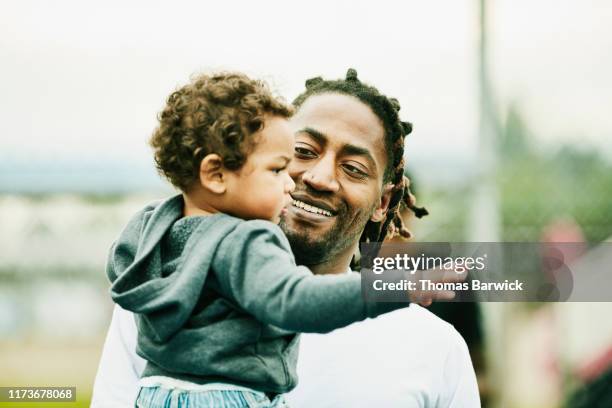 smiling man holding toddler son - black and white photo out door sport photos et images de collection