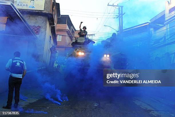 Marine in an armored personnel carrier throws a blue smoke flare in Rio de Janeiro's Morro da Mangueira shantytown as he advances through the slum's...