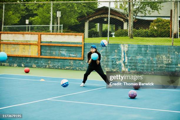 woman trying to avoid being hit during dodgeball game - ball passen stockfoto's en -beelden