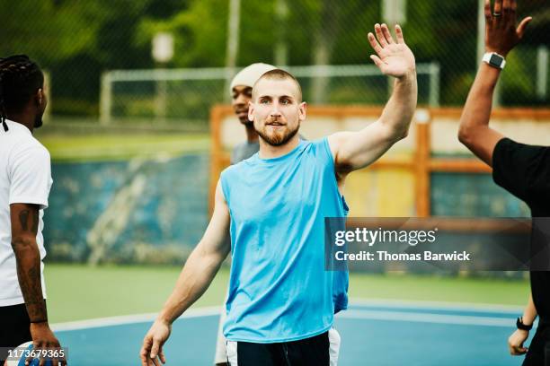 teammates high fiving after winning dodgeball game - adult male vest exercise stock pictures, royalty-free photos & images