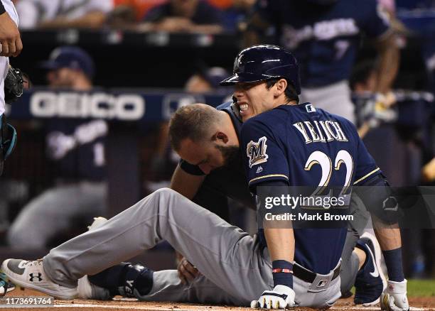 Christian Yelich of the Milwaukee Brewers is checked out by the medical staff after an injury from ball deflection in the first inning against the...