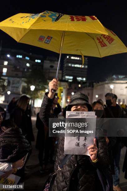 Protester hold a yellow umbrella and a placard during the demonstration. Protesters rallied at Trafalgar Square to demand democracy and justice in...