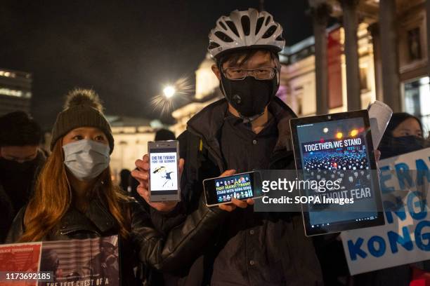 Protester hold phones and a tablet during the demonstration. Protesters rallied at Trafalgar Square to demand democracy and justice in Hong Kong and...